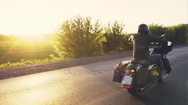 Motociclista a caballo en una carretera vacía al atardecer — Vídeos de Stock