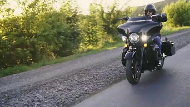 Een fietser op een krachtige motorfiets haasten langs de weg en de schittering van de zon vallen in de lens — Stockvideo