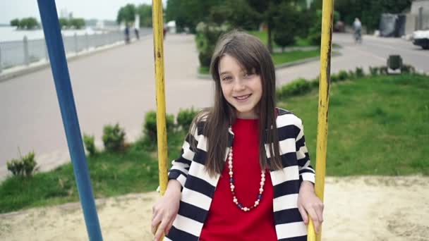 Mladá dívka se houpe na houpačce v parku v letním dni. — Stock video