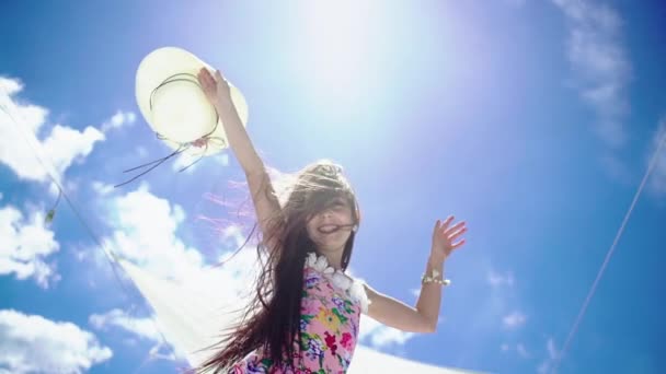 Una joven alegre en traje de baño con un gorro divertido saltando y regocijándose contra el fondo del cielo azul y el sol brillante . — Vídeos de Stock