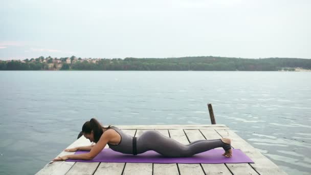 Athletic woman practising yoga on wooden pier — Stock Video