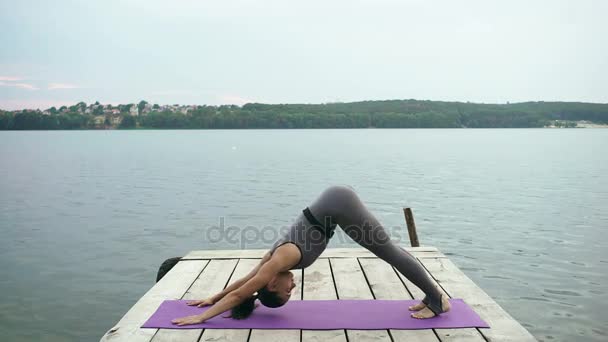 Woman practicing yoga on pier — Stock Video