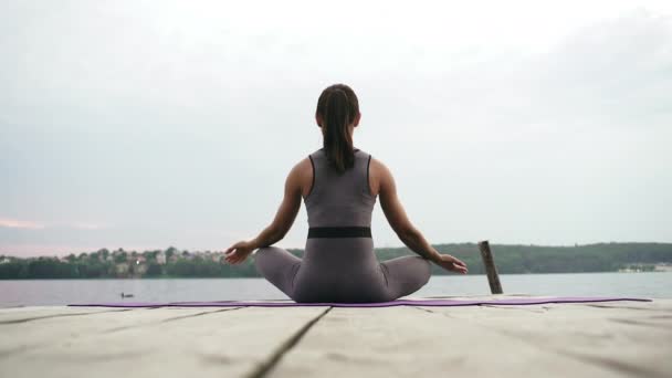 Young woman meditates in lotos position next to the sea — Stock Video