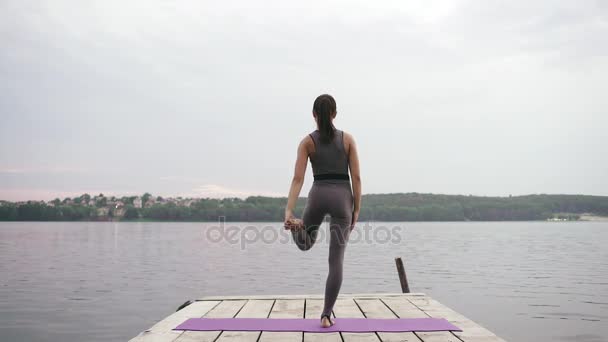 Girl practices yoga near the lake — Stock Video