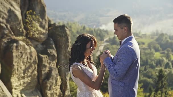 Šťastní novomanželé, drželi se za ruce v přírodě — Stock video