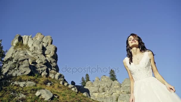 Mooie vrouw in witte jurk op mountain peak rots springen. Mooi meisje op zoek gelukkig en lachende. — Stockvideo