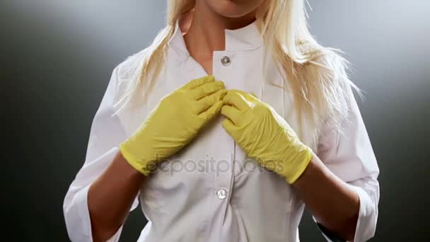 Спокуслива блондинка медсестра на чорному тлі з іронічним платтям для обличчя — стокове відео