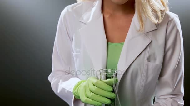 Woman looking down at partially empty beaker — Stock Video