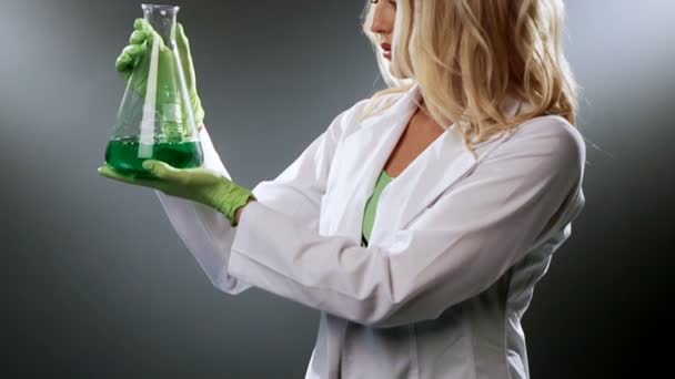 Científica femenina examina frasco con líquido verde atractiva investigadora haciendo experimento en laboratorio — Vídeo de stock