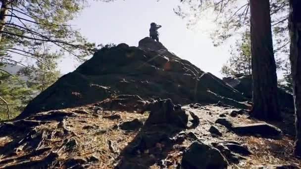 Homem no topo de uma rocha íngreme na floresta — Vídeo de Stock