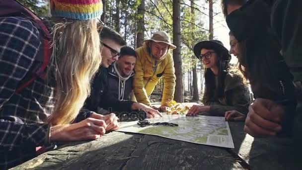 Група друзів обговорюють карту в лісі — стокове відео