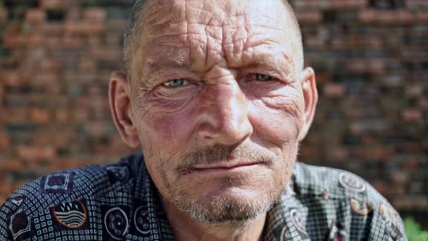 Portret van een arme oude bejaarde man die schamper naar de camera kijkt — Stockvideo