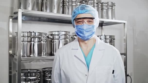 Porträtt av en säker läkare i sin arbetsmiljö mot rostfritt stål rack bakgrund — Stockvideo