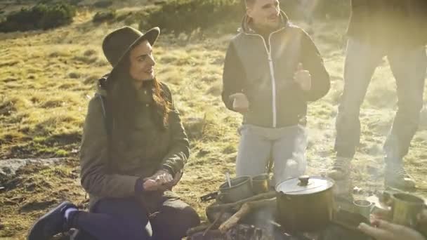 Gruppo di amici seduti al focolare mattutino e divertirsi sullo sfondo delle montagne — Video Stock