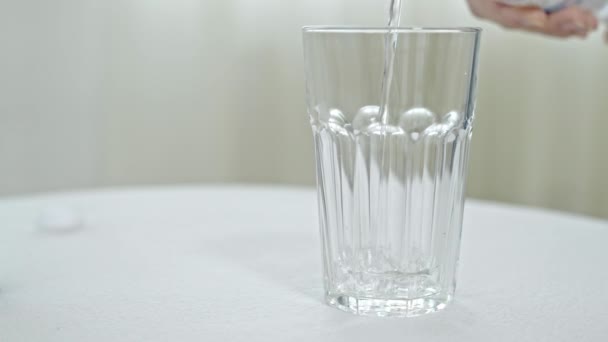 Verser l'eau de la bouteille dans du verre sur fond blanc — Video