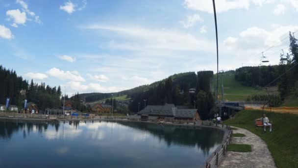 BUKOVEL, UCRÂNIA - 4 MAIO 2016: O elevador em uma estância de esqui. Casas para turistas e lago com peixes . — Vídeo de Stock