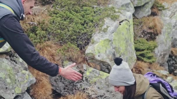 Erős ember segít a lánynak, hogy mászni a hegyre — Stock videók