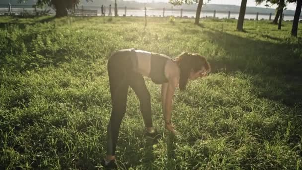 Mujer activa haciendo ejercicios de estiramiento al aire libre en un día soleado. Mujer haciendo ejercicios de estiramiento al aire libre . — Vídeos de Stock