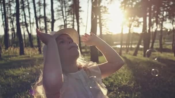 Młoda dziewczyna gra z baniek mydlanych na słoneczny dzień — Wideo stockowe