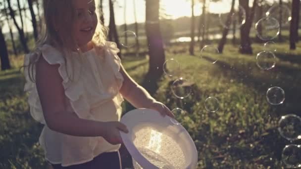 Młoda wesoła dziewczyna połowu baniek mydlanych w kapelusz słoneczny dzień. — Wideo stockowe