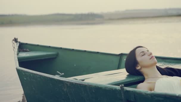 Jeune fille couchée dans un bateau flottant sur le lac . — Video