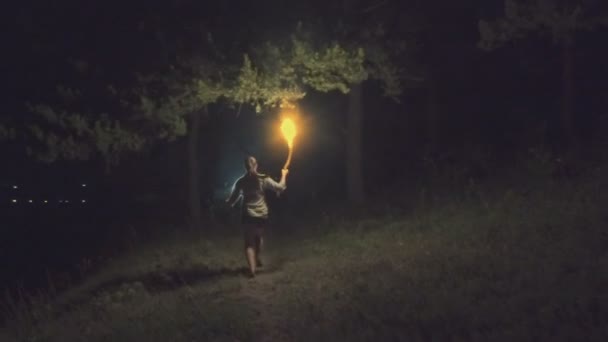 Хоробра дівчина подорожує по нічному лісу, тримаючи вогненний факел в руці. Повільний рух . — стокове відео