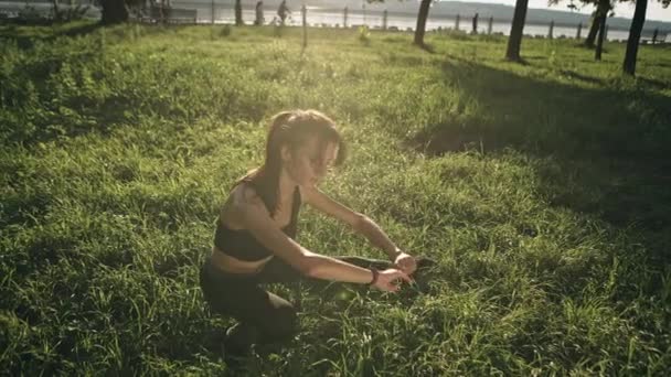 Mladá žena cvičení venku táhne jeden z jejích nohou — Stock video