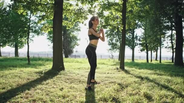 Hermosa chica caucásica practicando deporte haciendo sentadilla haciendo ejercicio en el parque — Vídeos de Stock