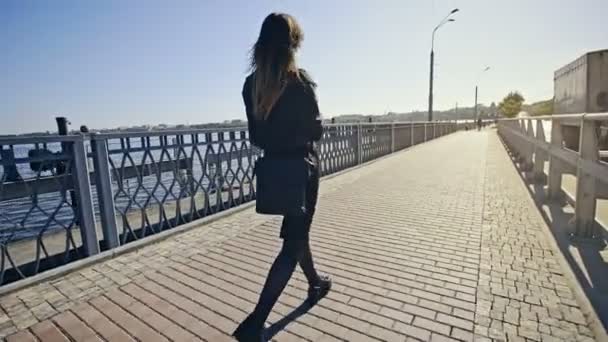 Pretty young girl holding pc tablet and cup of coffee while walking outdoors at the city street — Stock Video