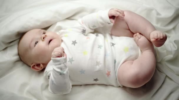 幸福心满意足的新生儿躺在它的背部在白色的毯子挥舞着它的手臂在空中和踢它的腿 — 图库视频影像