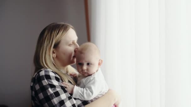 Yatak odasında parlak bir pencere yakınında yeni doğmuş bir bebek ile mutlu anne — Stok video