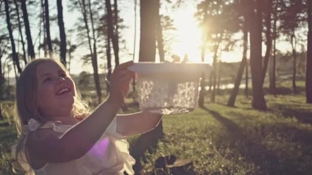 Legrační malá holčička chytání mýdlové bubliny v létě na přírodu má malá holčička, happy fun s veselý úsměv na tváři. Bezstarostné dítě běžet a skákat na zelené letní louku, chytání mýdlové bubliny — Stock video