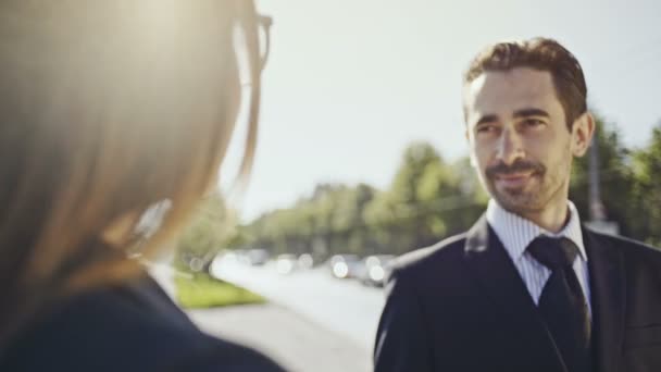 Szczęśliwy biznesmenów i business Panie patrząc sobie w oczy. Letni dzień na ulicach miasta, w pobliżu strumienia samochodów. — Wideo stockowe