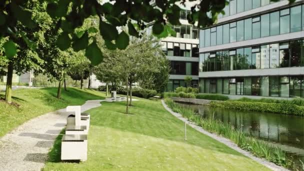 Parque con arbustos verdes, bancos frente al Centro de Negocios — Vídeo de stock