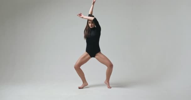 Молодая танцовщица балета растягивается. Видеоклип молодой босиком танцовщицы балета, растянувшейся в студии . — стоковое видео