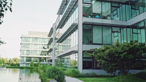 Moderna glas frontade kontorsbyggnader i en park — Stockvideo