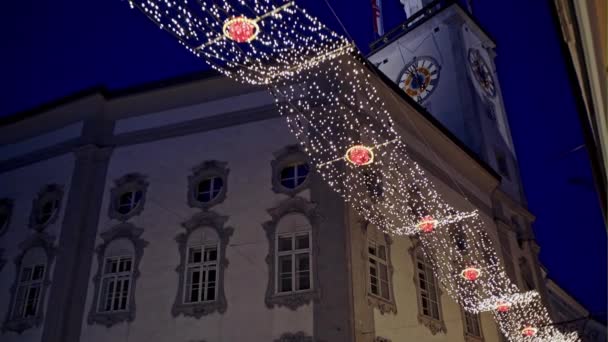 Desde abajo plano de guirnaldas de colores y luces colgando en la calle contra la antigua catedral en Salzburgo, Austria — Vídeos de Stock