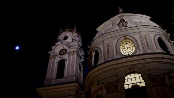 From below shot of cathedral exterior with tower and glowing window in night time, Salzburg, Austria — Stock Video