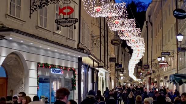 Salzburg, Austria - 27 grudnia 2017: Widok ludzi chodzących na ulicy Salzburga z świecące girlandy i sklepy — Wideo stockowe