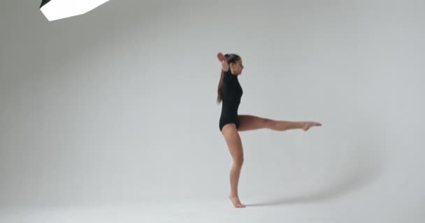 Молодая красивая танцовщица в современном стиле позирует на фоне студии — стоковое видео