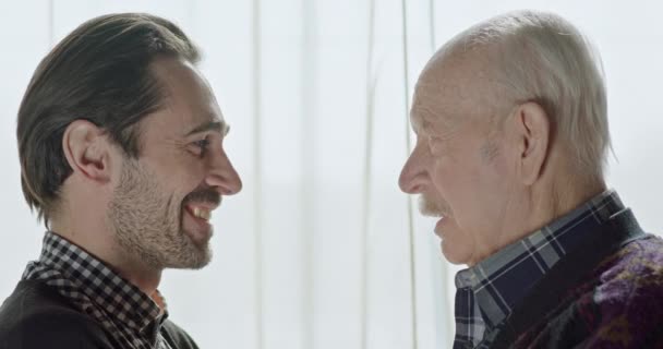 Hombre de mediana edad y su padre hablando y luego abrazándose en alivio sonriendo, riendo y tomándose de la mano . — Vídeos de Stock