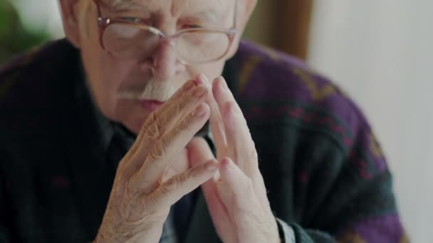 Worried old man banging his fingers together. Worried old man banging his fingers together before suddenly moving to the side with an intense expression to start a conversation. — Stock Video