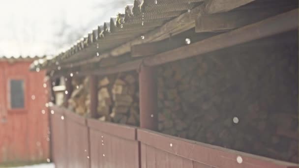Der Frühling ist da - Schmelzschneetropfen mit Wasser fließen vom Dach über das gehäckselte Holz im Dorf — Stockvideo