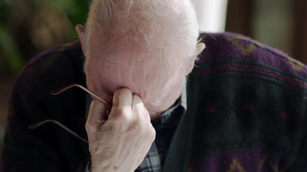 Пожилой человек преодолел горе сидя в очках в руке и голову склонился, прежде чем смотреть вверх плача . — стоковое видео