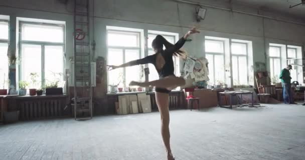 Mooie jonge meisje hedendaagse dans dansen in de ruime grote kunststudio. Vrouw treinen de flexibiliteit van haar lichaam — Stockvideo