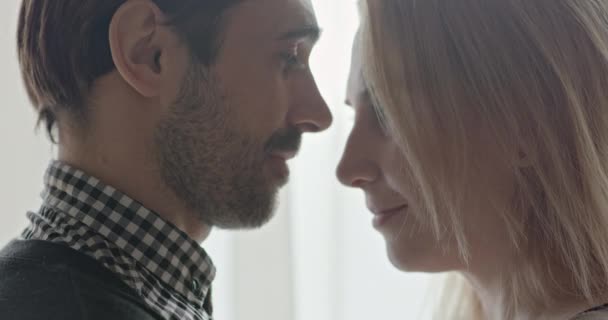 Les sentiments sincères d'amour de deux adultes debout face à face au niveau d'un baiser, mais sont intégrés l'un dans l'autre en face de la lumière vive de la fenêtre . — Video
