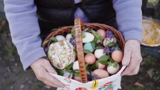 Cesta de Pascua en las rodillas de una anciana en el día antes de las vacaciones sentado en el patio en el verano . — Vídeos de Stock