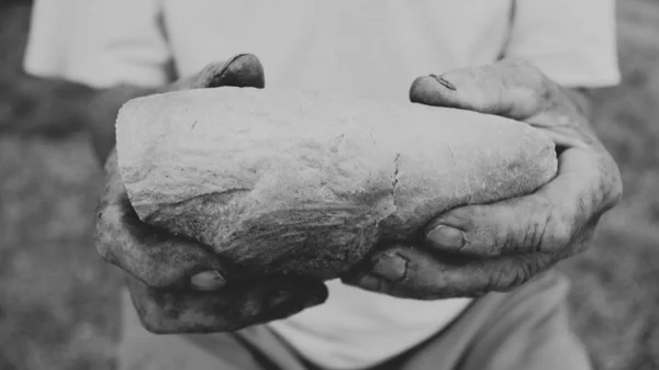 Alter Mann hält ein Stück Brot und teilt es — Stockfoto
