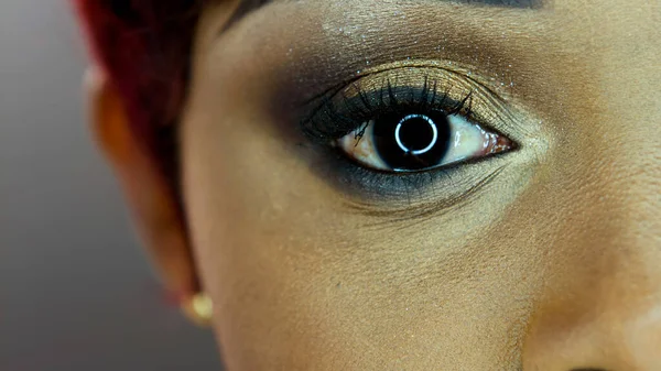 Close up imagem de olho de mulher negra contra fundo cinza — Fotografia de Stock