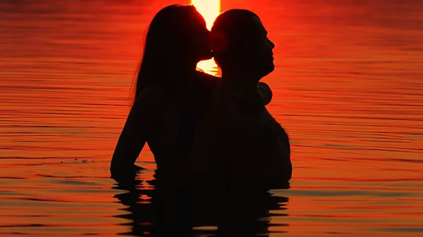 Mädchen und Junge schwimmen bei Sonnenuntergang — Stockfoto